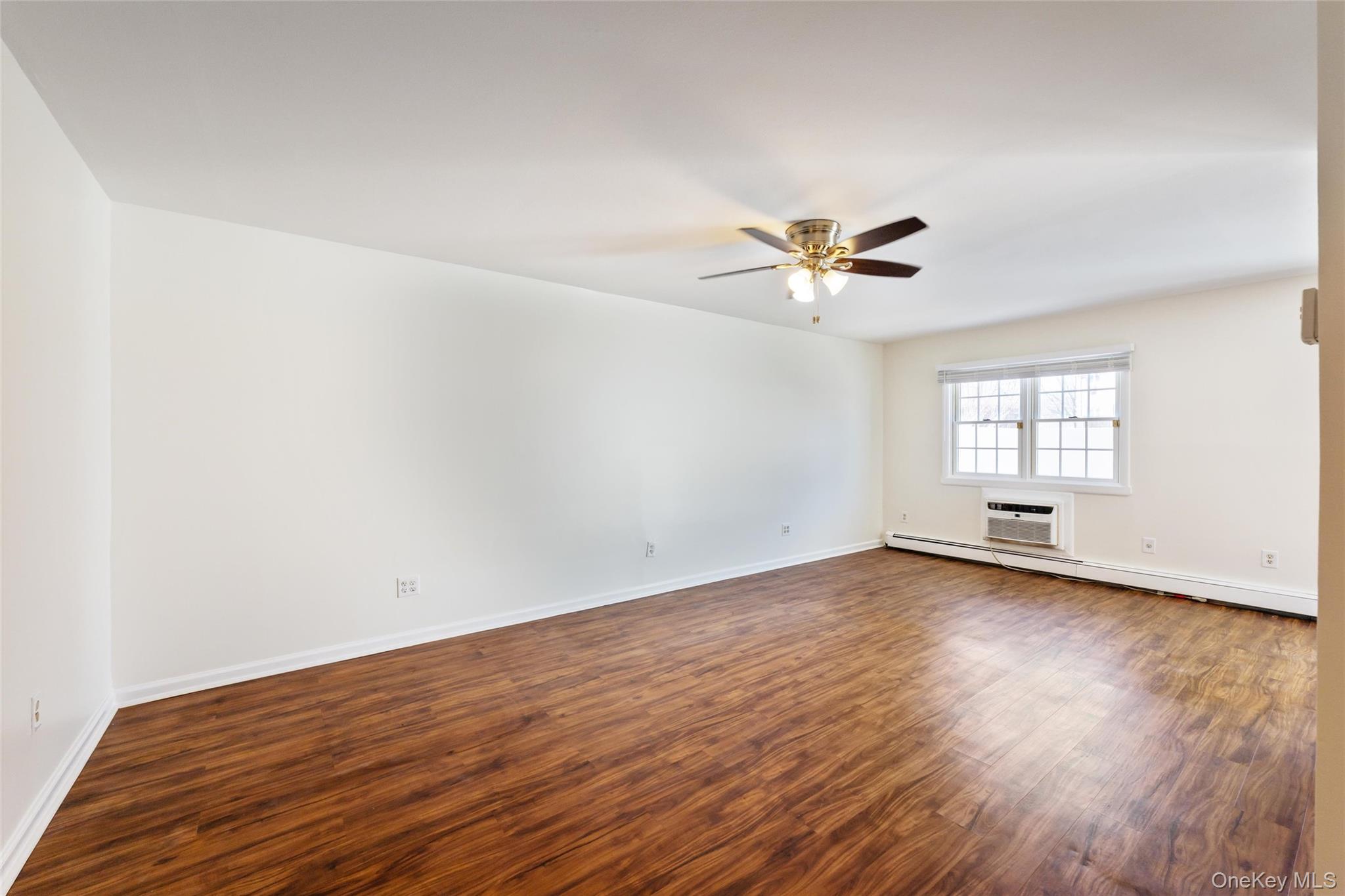 460 Old Town Road, Unit 20F Port Jefferson Station, NY 11776 - Photo 5 of 22 an empty room with wooden floor and ceiling fan
