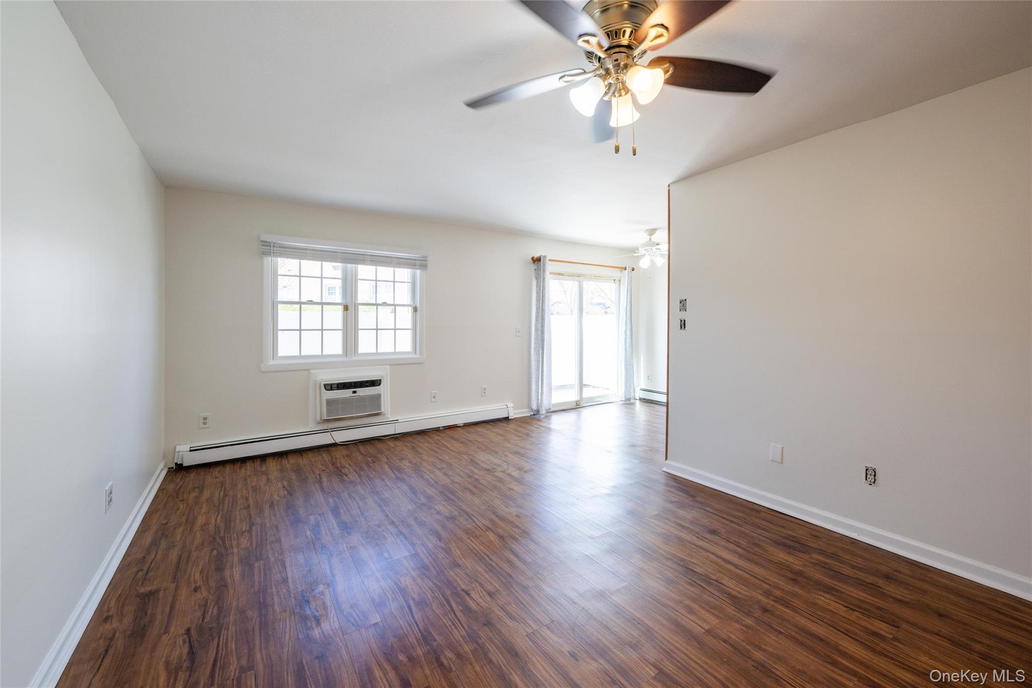 460 Old Town Road, Unit 20F Port Jefferson Station, NY 11776 - Photo 6 of 22 an empty room with wooden floor chandelier fan and windows