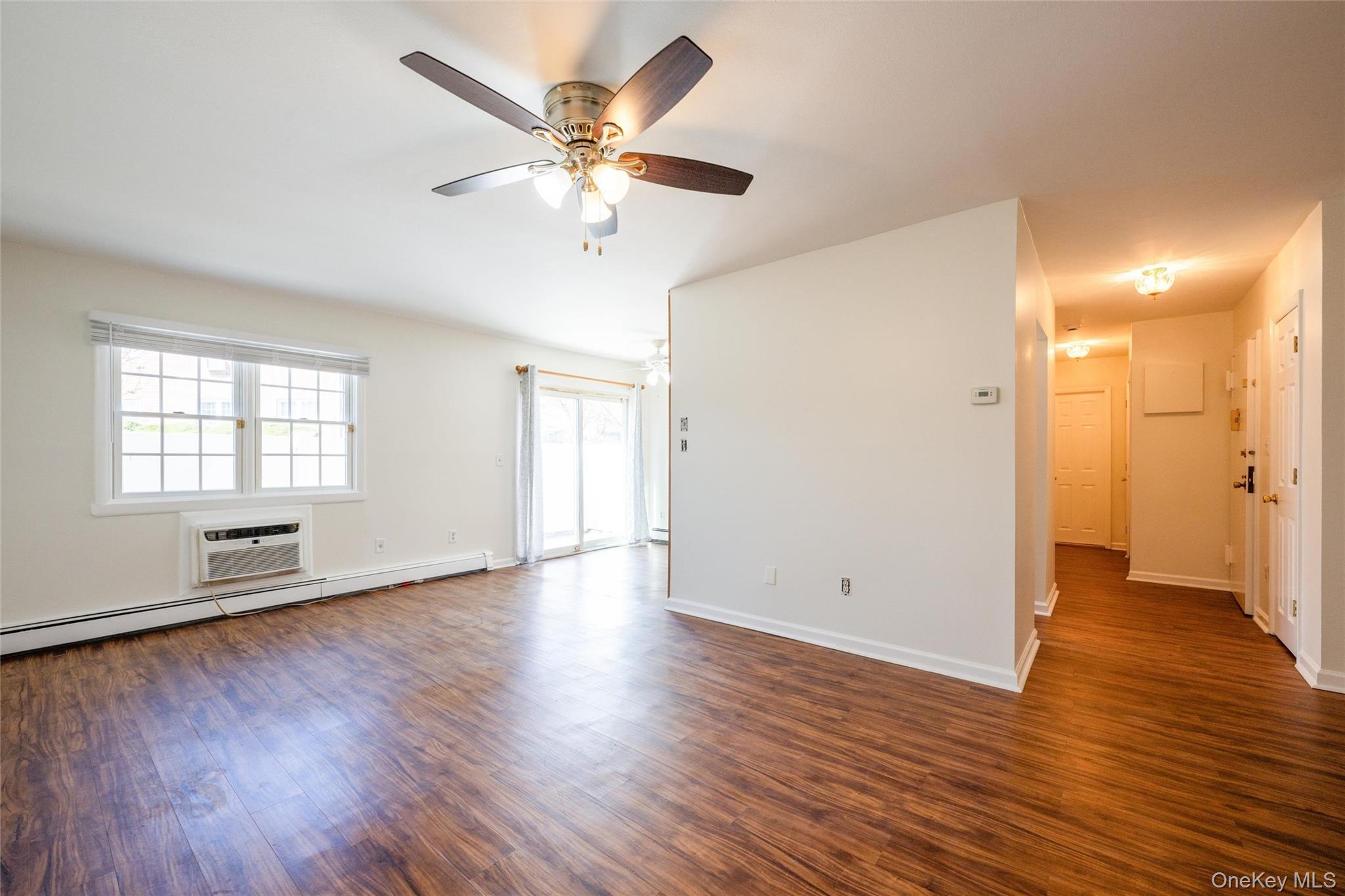 460 Old Town Road, Unit 20F Port Jefferson Station, NY 11776 - Photo 9 of 22 an empty room with wooden floor and windows