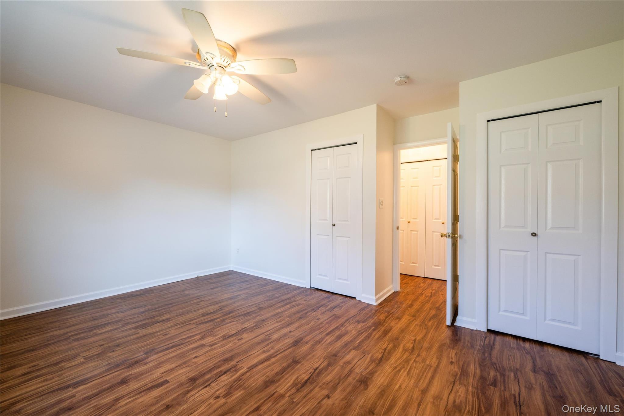 460 Old Town Road, Unit 20F Port Jefferson Station, NY 11776 - Photo 10 of 22 an empty room with wooden floor and a ceiling fan