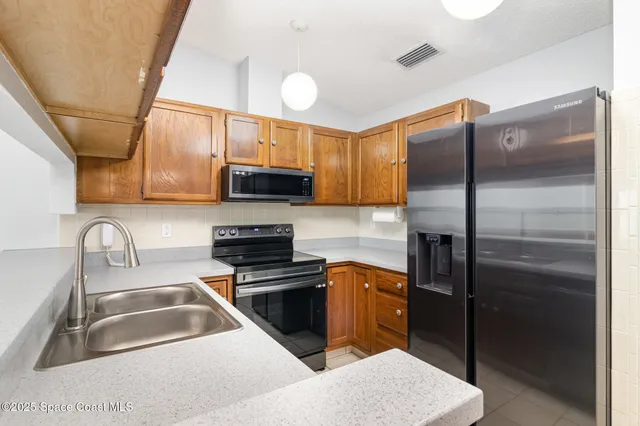a kitchen with stainless steel appliances granite countertop a sink a stove and a refrigerator