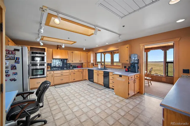 a kitchen with stainless steel appliances kitchen island granite countertop a refrigerator oven a sink dishwasher and white cabinets with wooden floor
