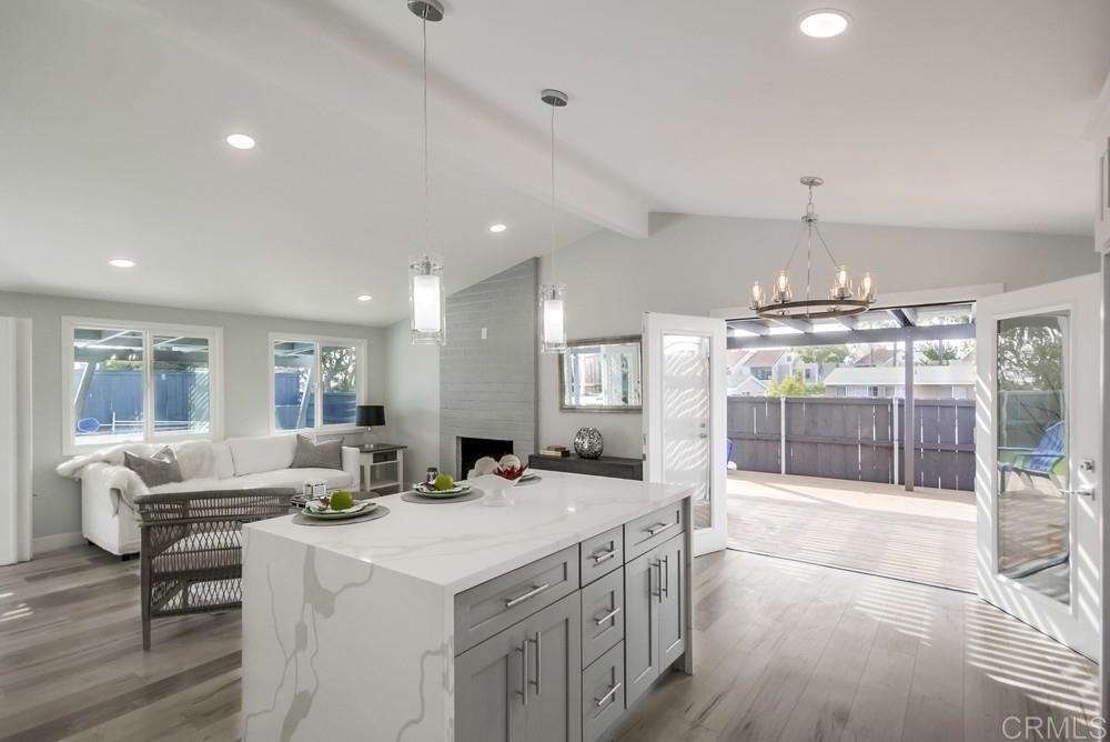 a living room with stainless steel appliances furniture a chandelier and a view of kitchen