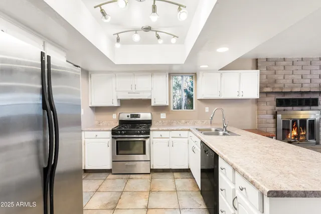 a kitchen with stainless steel appliances granite countertop a sink stove refrigerator and cabinets