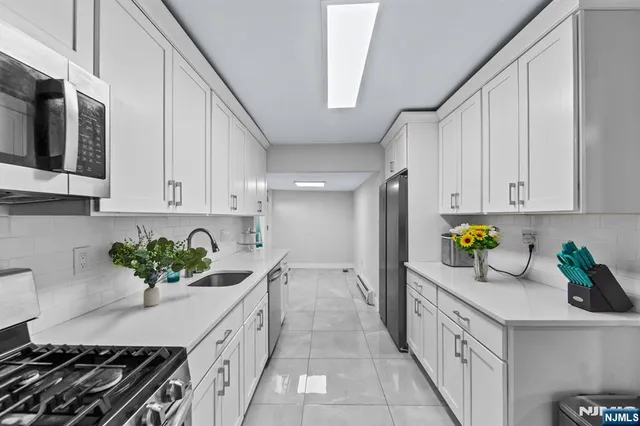 a kitchen with stainless steel appliances a sink a stove cabinets and a window