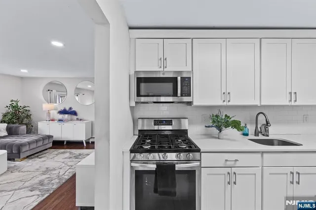 a kitchen with granite countertop white cabinets and stainless steel appliances