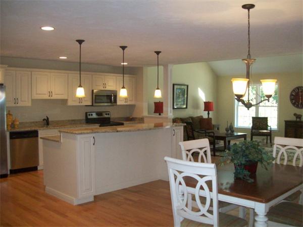 20 Riley Road, Unit 11 Lunenburg, MA 01462 - Photo 4 of 8 a kitchen with stainless steel appliances wooden floor dining table chairs and wooden floor