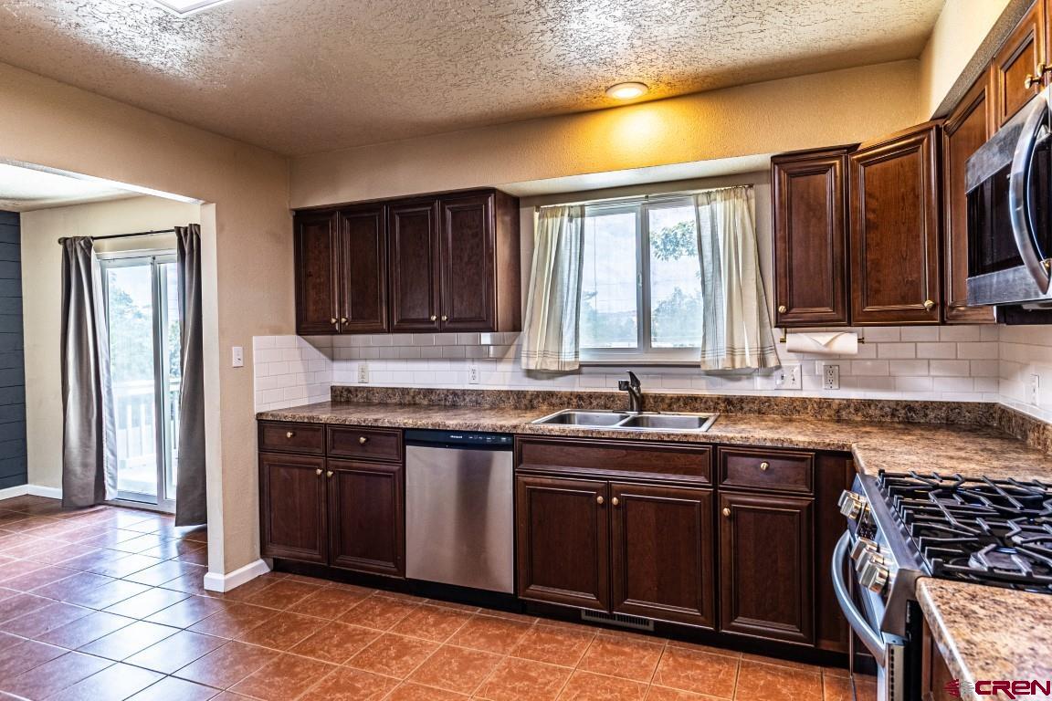 5705 Ravella Drive Farmington, NM 87402 - Photo 5 of 35 a kitchen with stainless steel appliances granite countertop a stove a sink and a microwave
