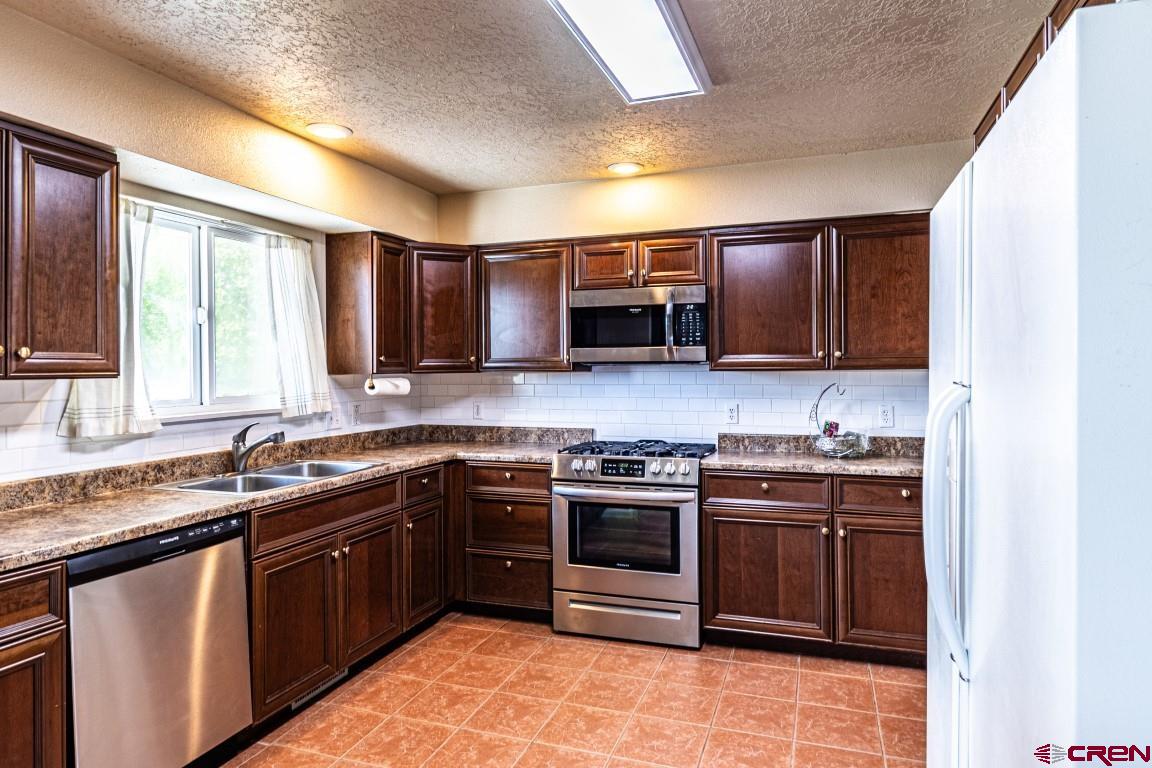 5705 Ravella Drive Farmington, NM 87402 - Photo 6 of 35 a kitchen with stainless steel appliances granite countertop a sink stove microwave and cabinets