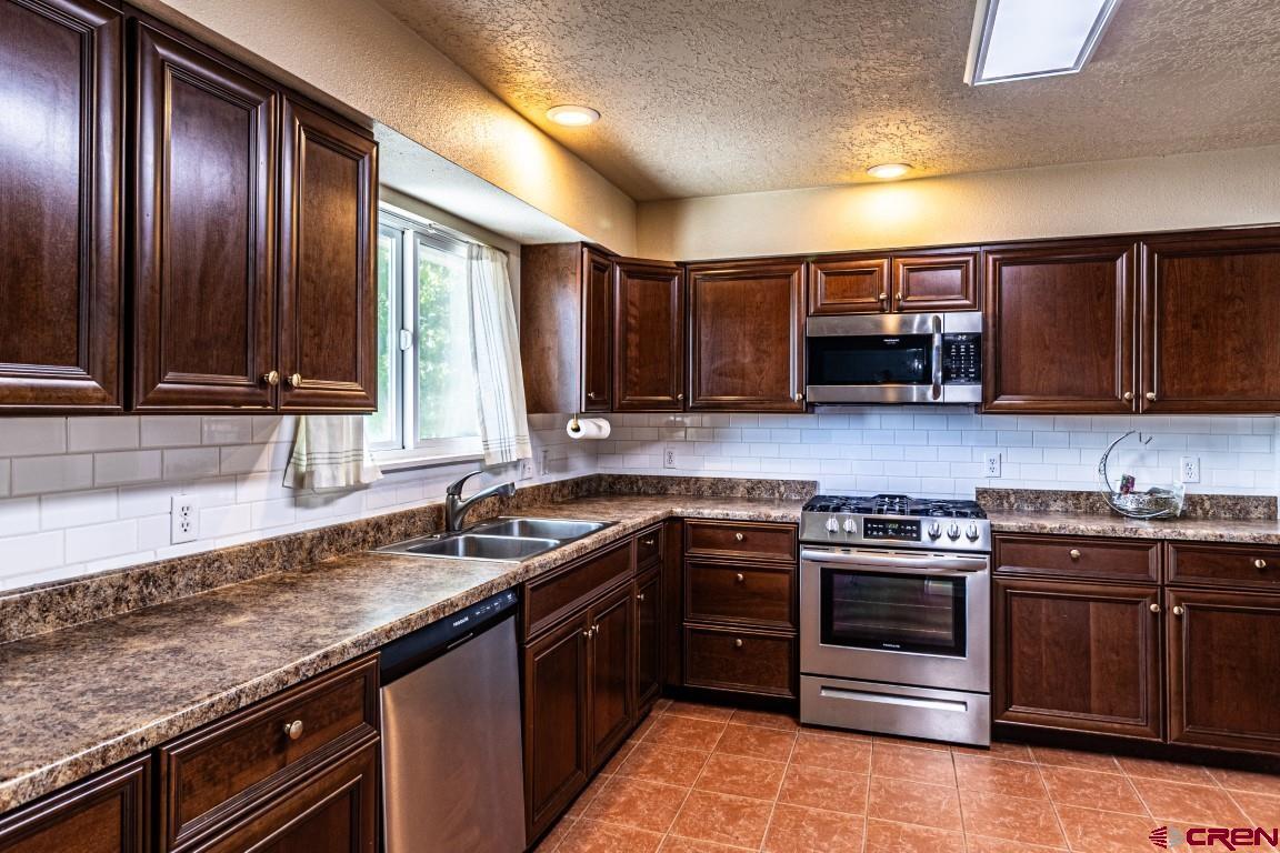 5705 Ravella Drive Farmington, NM 87402 - Photo 7 of 35 a kitchen with stainless steel appliances granite countertop wooden cabinets stove a sink and dishwasher