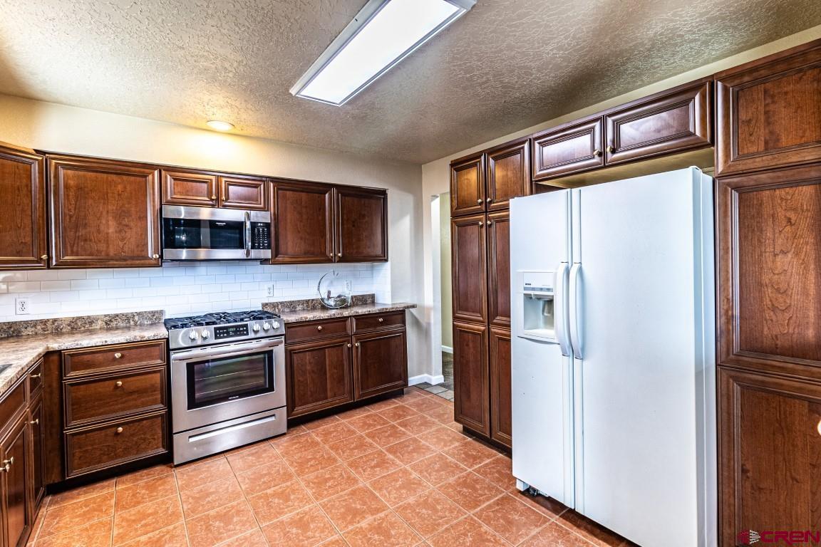 5705 Ravella Drive Farmington, NM 87402 - Photo 8 of 35 a kitchen with stainless steel appliances granite countertop a refrigerator stove and microwave