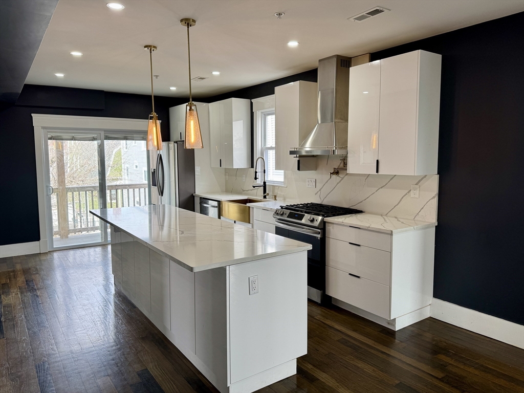 567 Park Street, Unit 3 Boston, MA 02124 - Photo 1 of 11 a kitchen with stainless steel appliances kitchen island a large counter top a stove a refrigerator a sink and a large window