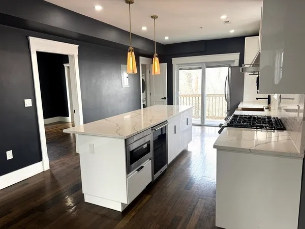 a large kitchen with stainless steel appliances a large counter top a stove and a refrigerator