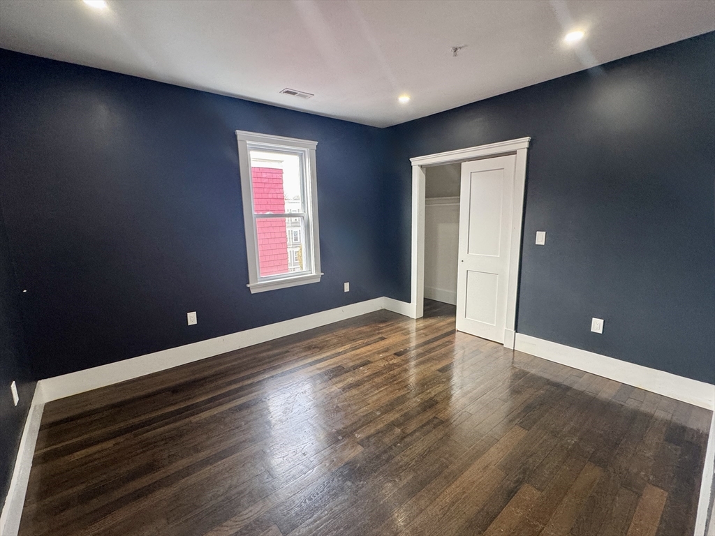 567 Park Street, Unit 3 Boston, MA 02124 - Photo 6 of 11 an empty room with wooden floor and windows