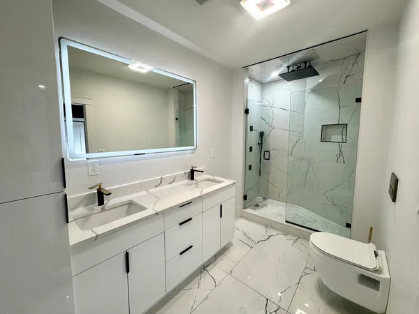 a bathroom with a double vanity sink toilet mirror and shower