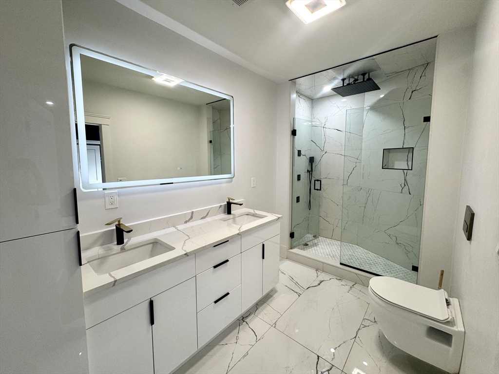 567 Park Street, Unit 3 Boston, MA 02124 - Photo 7 of 11 a bathroom with a double vanity sink toilet mirror and shower