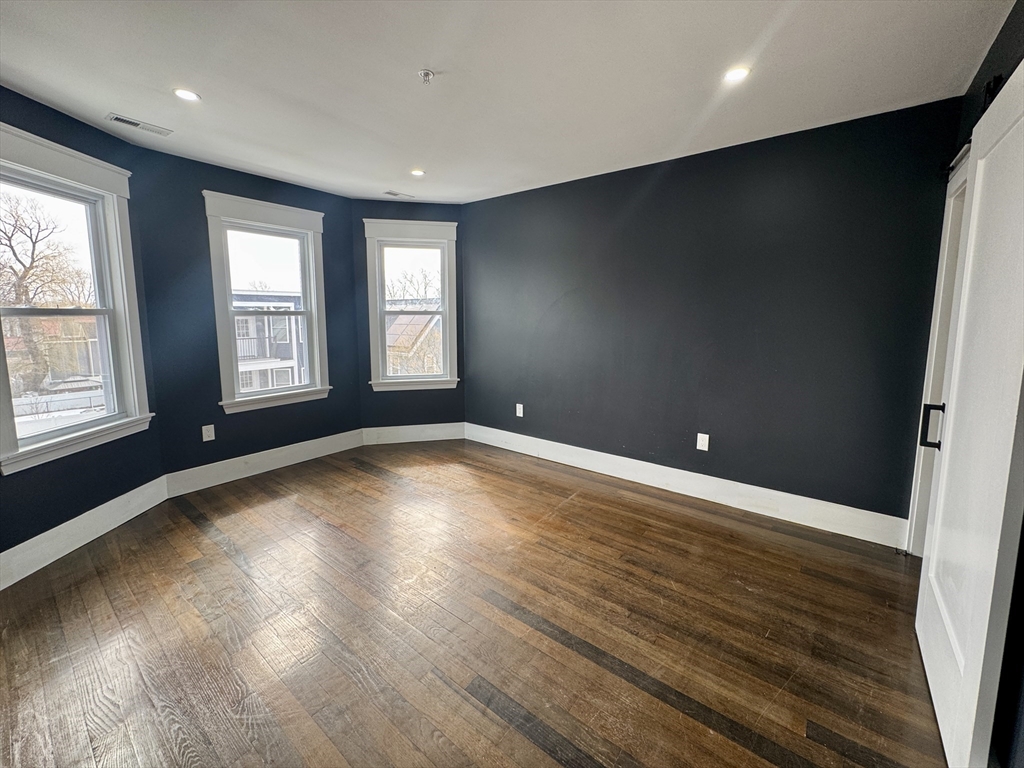 567 Park Street, Unit 3 Boston, MA 02124 - Photo 8 of 11 an empty room with wooden floor and windows