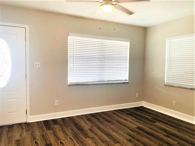 a view of an empty room with wooden floor and a window