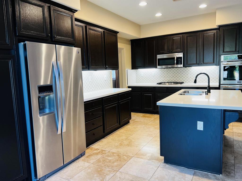 2834 Rancho Pancho Carlsbad, CA 92009 - Photo 19 of 73 a kitchen with stainless steel appliances granite countertop a refrigerator a stove a sink and dishwasher