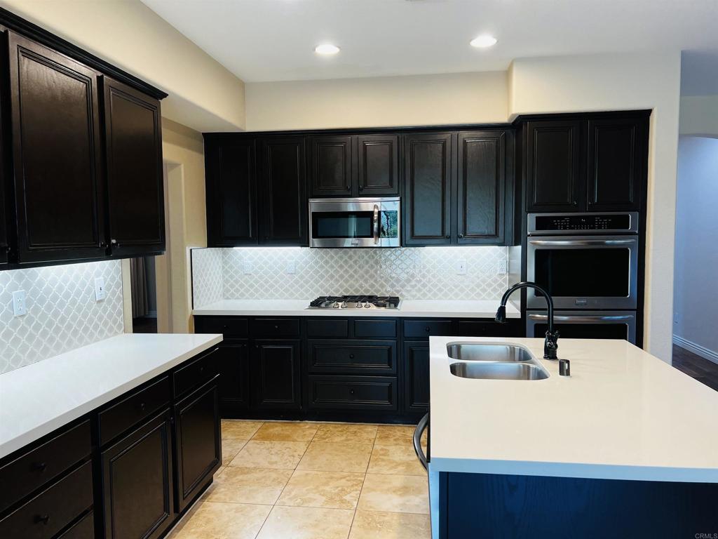 2834 Rancho Pancho Carlsbad, CA 92009 - Photo 21 of 73 a kitchen with a sink and a stove top oven with wooden floor