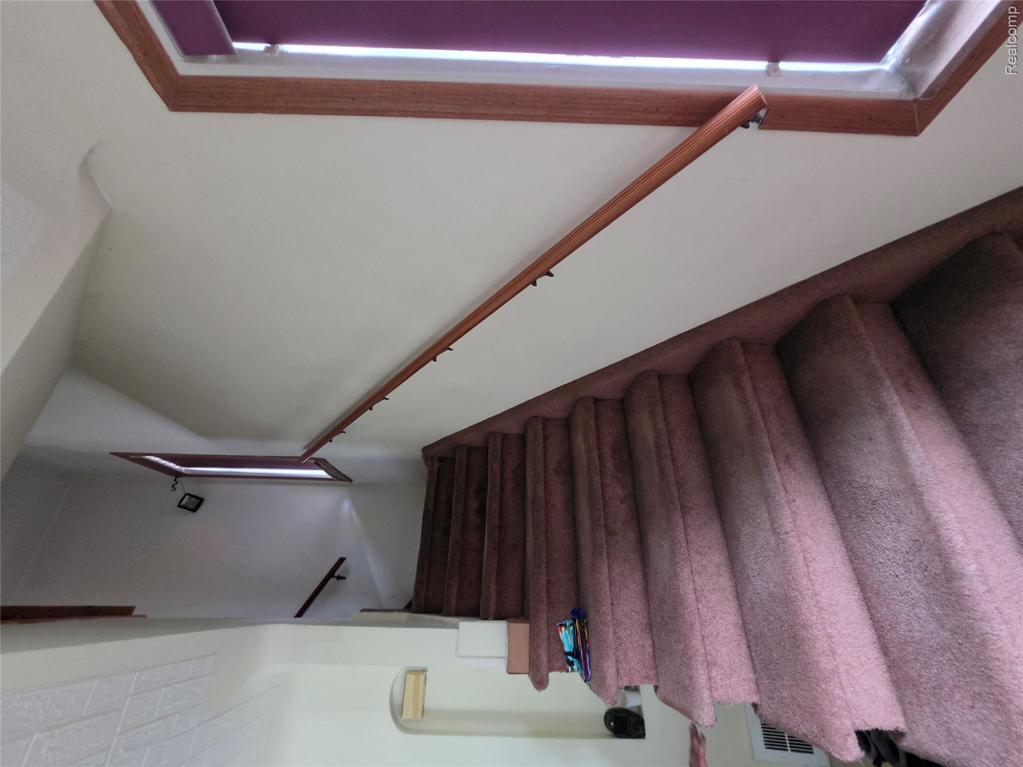 15832 Griggs Street Detroit, MI 48238 - Photo 14 of 24 Carpeted staircase with a wood handrail and trim, featuring multiple windows providing natural illumination