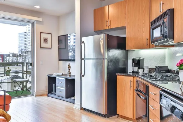 a kitchen with stainless steel appliances kitchen island granite countertop a refrigerator a sink a stove top oven a dining table and chairs