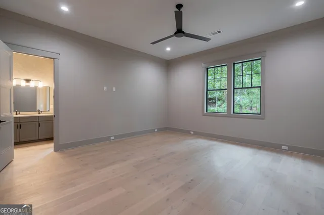 a view of a white house with a small yard plants and a large tree
