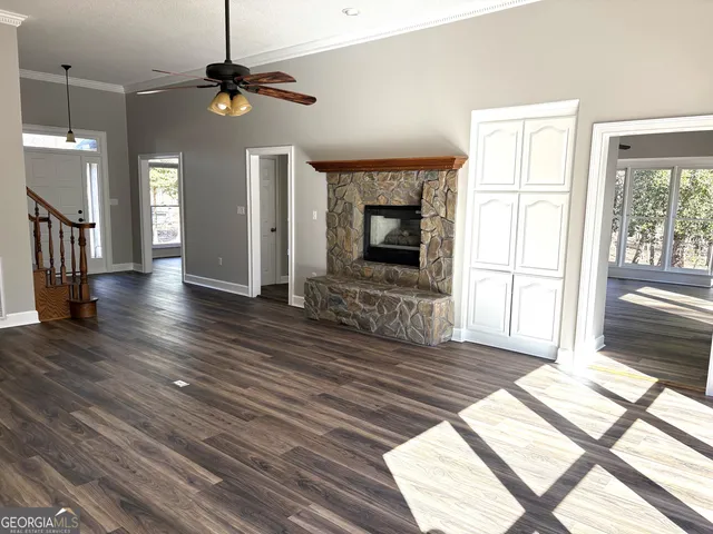 a view of an empty room with wooden floor fireplace and a window