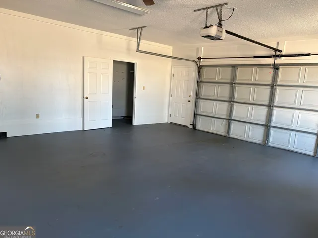an empty room with chandelier fan and windows