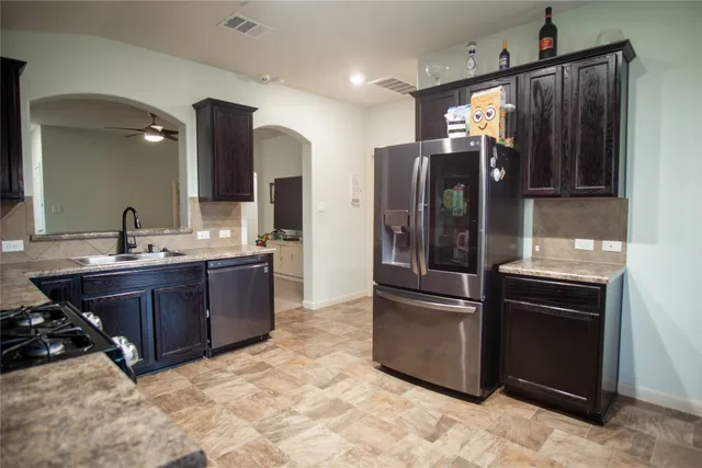 a kitchen with stainless steel appliances granite countertop a refrigerator a stove and a sink