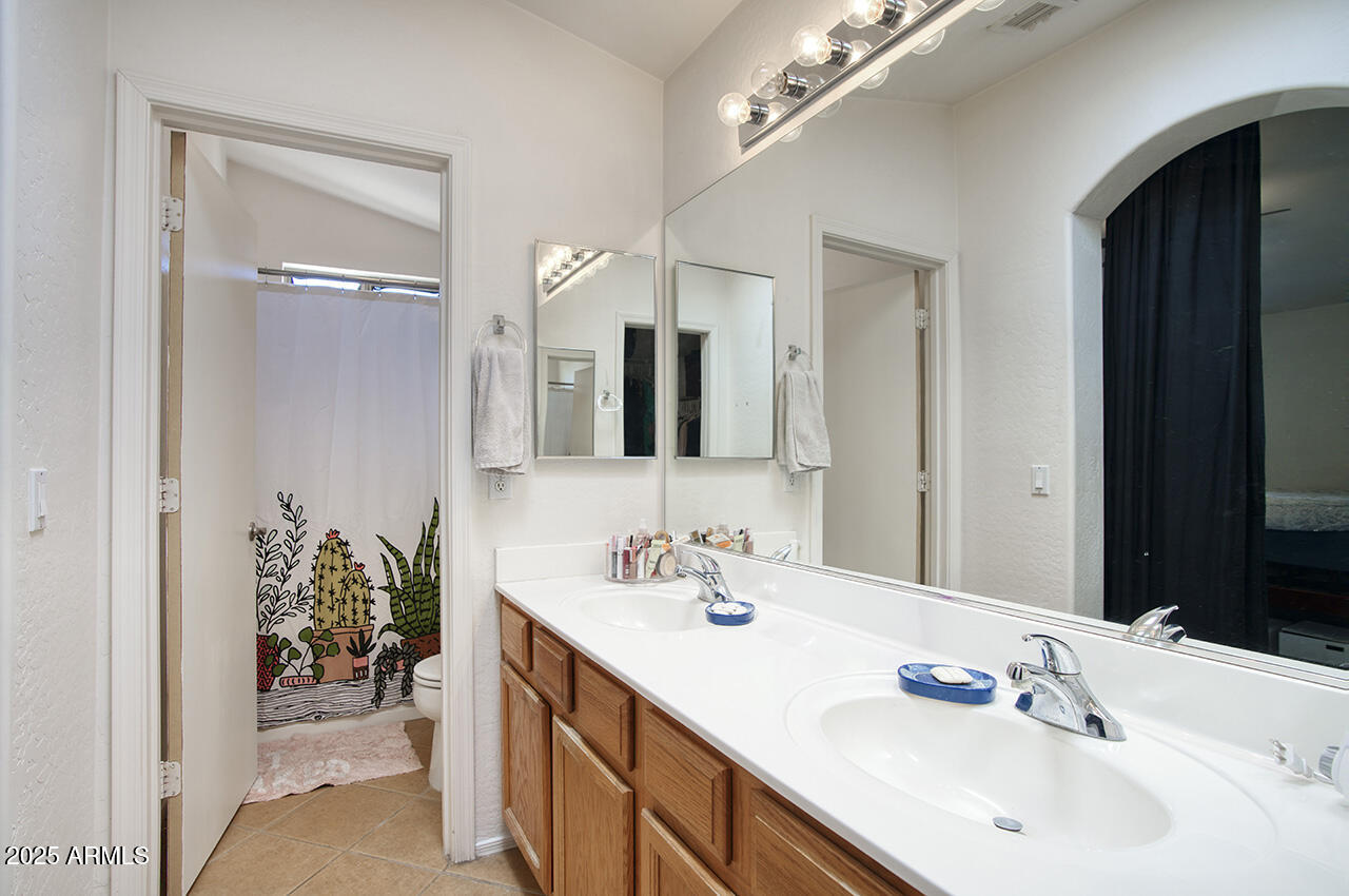 10617 West Coronado Road Avondale, AZ 85392 - Photo 16 of 32 a en suite bathroom with a double vanity sink and large mirror