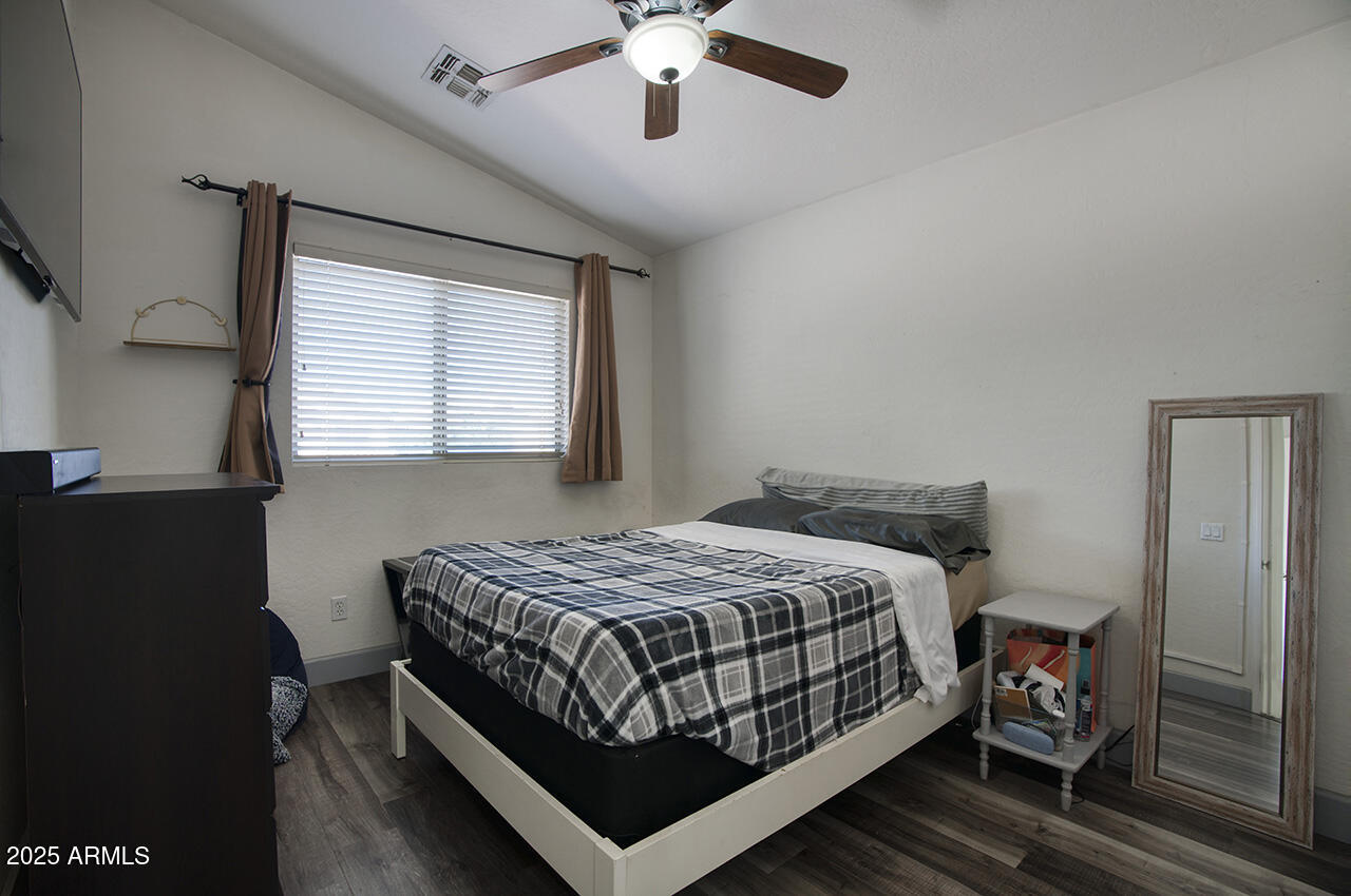 10617 West Coronado Road Avondale, AZ 85392 - Photo 17 of 32 a bedroom with a bed next to a window with a chandelier