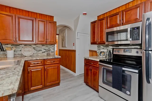 a kitchen with stainless steel appliances granite countertop a stove top oven a sink dishwasher and a microwave oven with wooden cabinets