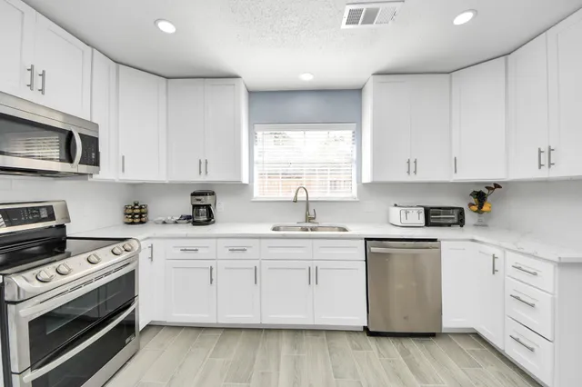 a kitchen with cabinets appliances a sink and a window