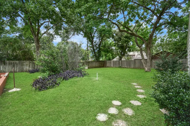 a view of a house with a yard and a large tree