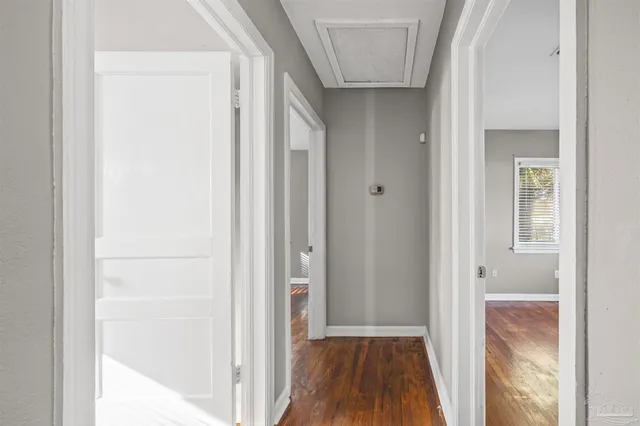 a view of a hallway with wooden floor and a bathroom