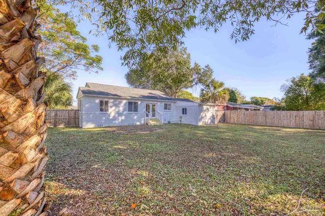a view of a yard in front of a house with a large tree