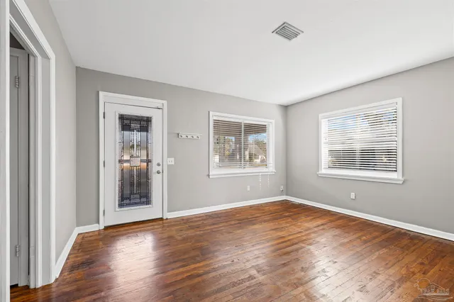 a view of empty room with wooden floor and fan