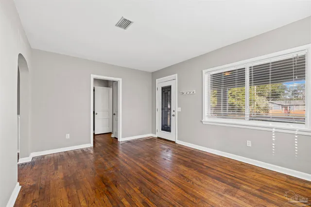 a view of an empty room with wooden floor and a window