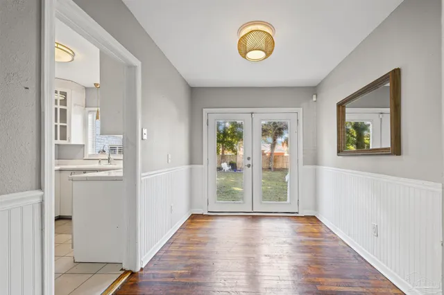 a view of a hallway to a livingroom with wooden floor and windows