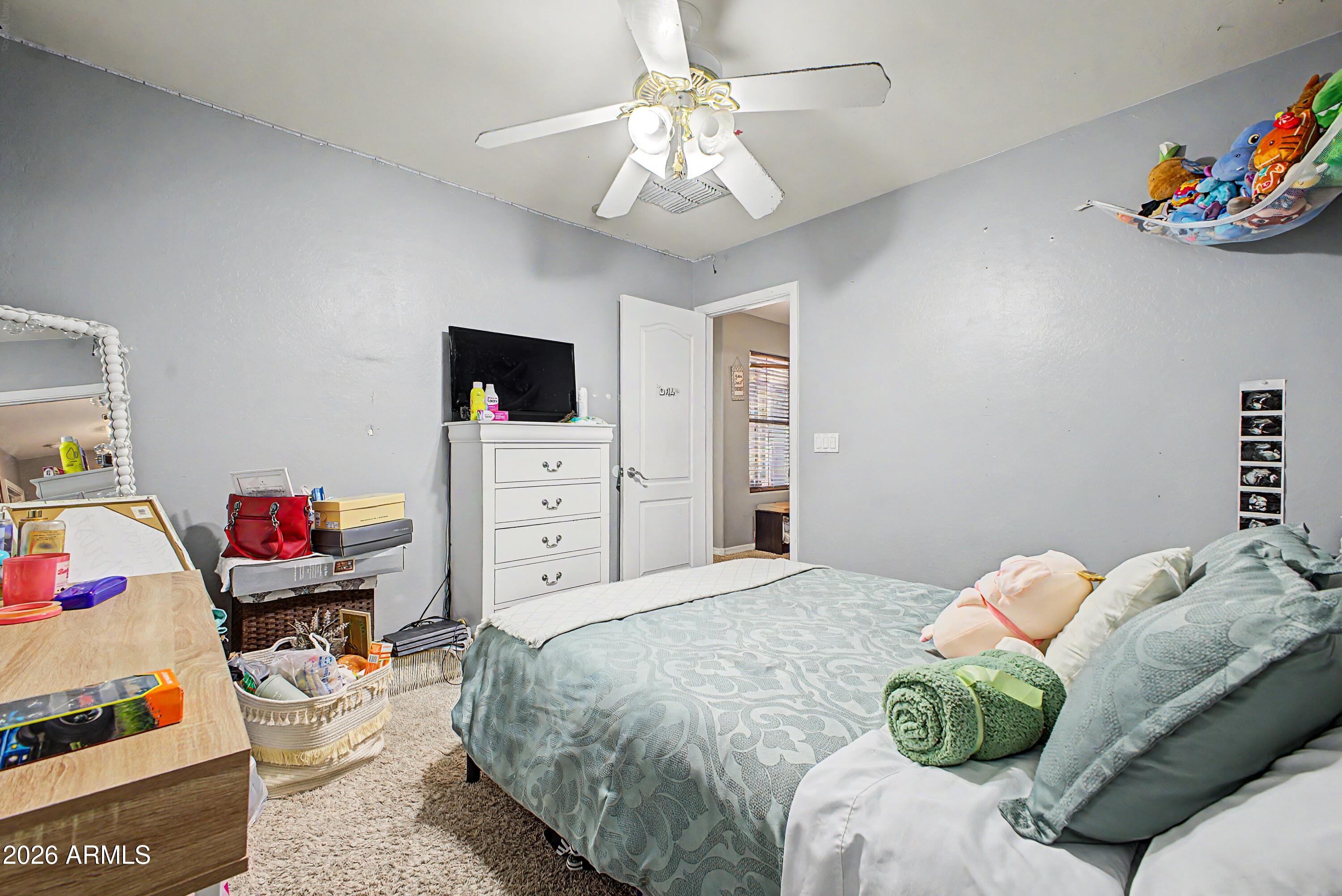 25652 West Rio Vista Lane Buckeye, AZ 85326 - Photo 23 of 32 a bedroom with a bed and a chandelier