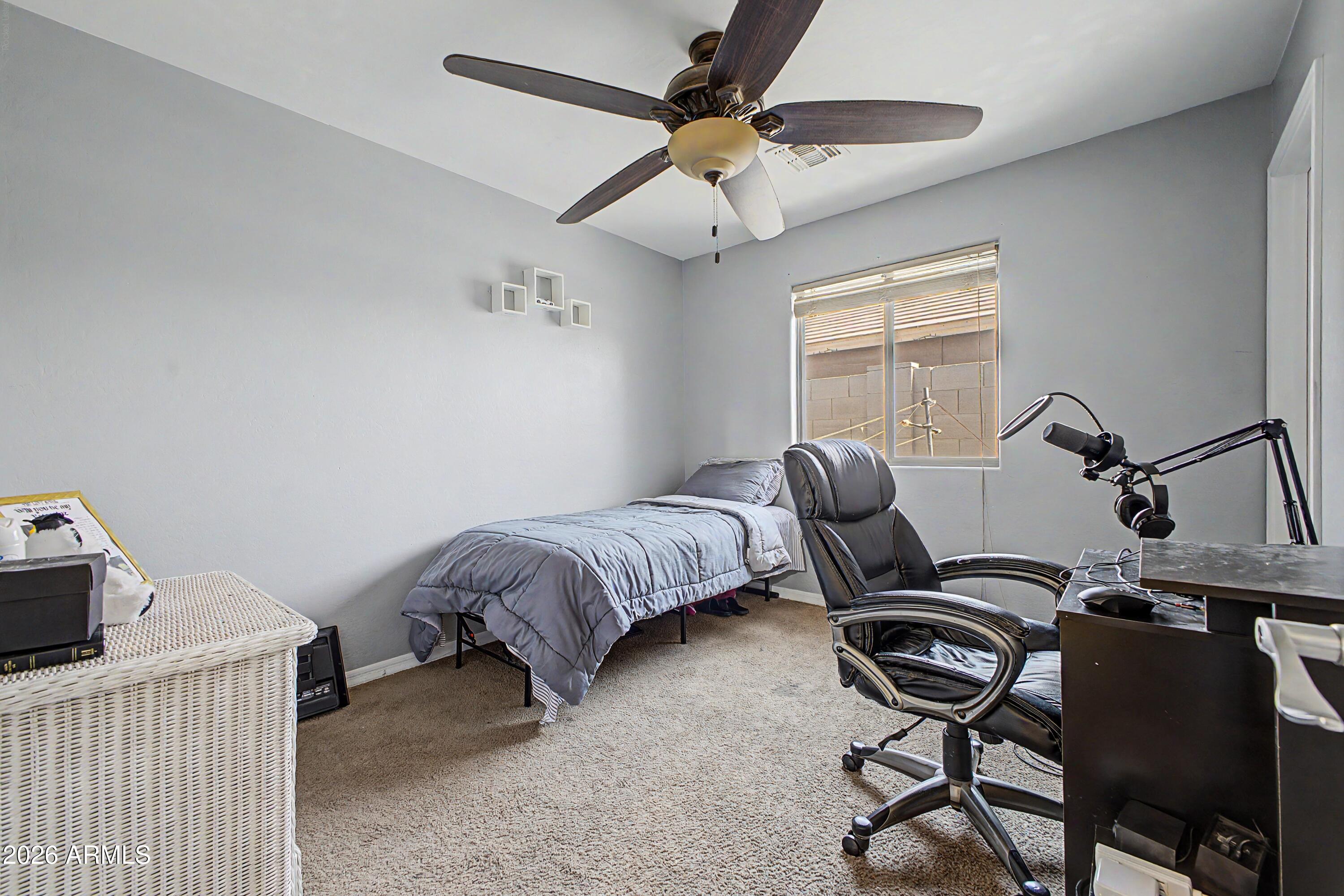 25652 West Rio Vista Lane Buckeye, AZ 85326 - Photo 24 of 32 a bedroom with a bed and a chandelier