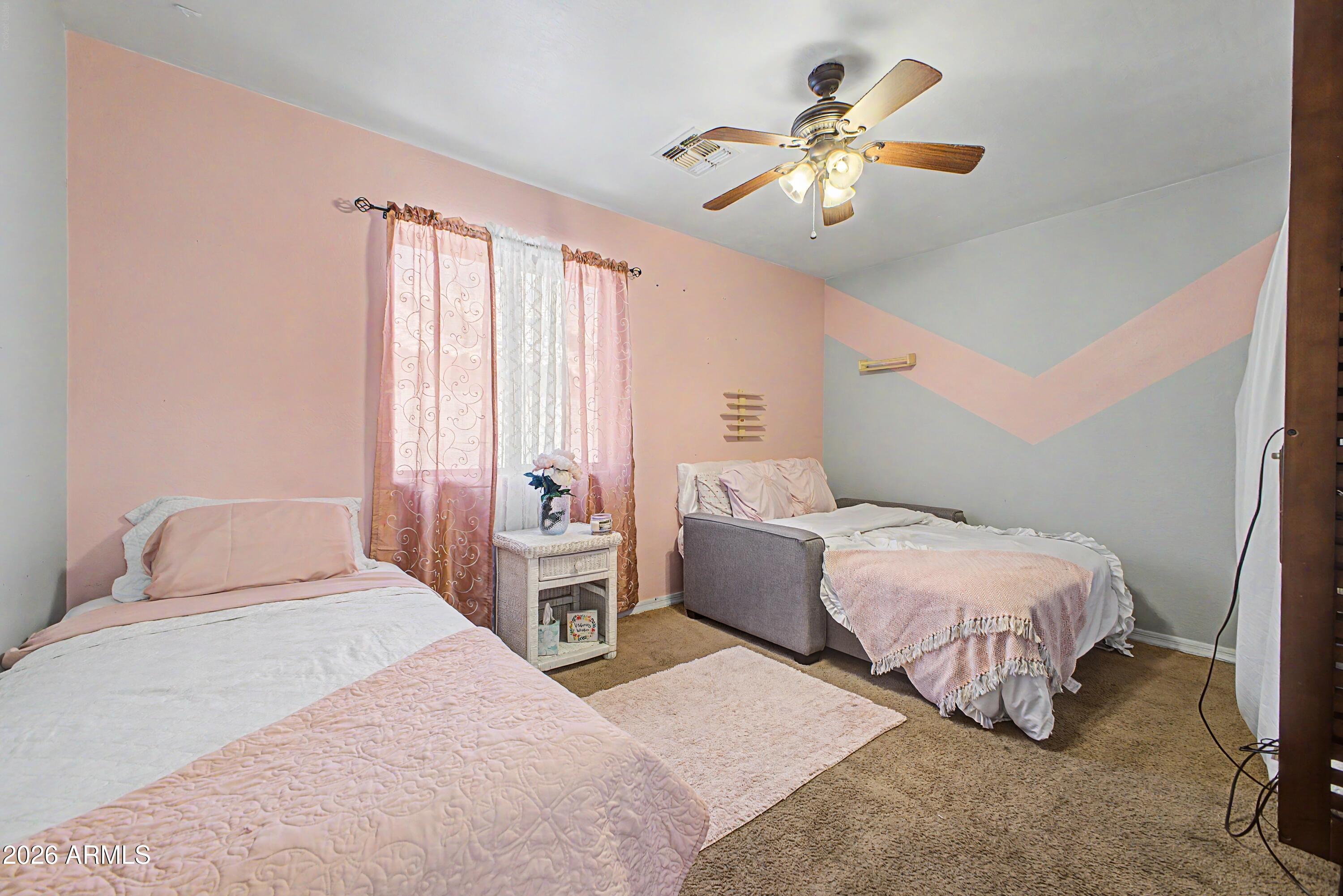 25652 West Rio Vista Lane Buckeye, AZ 85326 - Photo 28 of 32 a bedroom with two beds and a chandelier