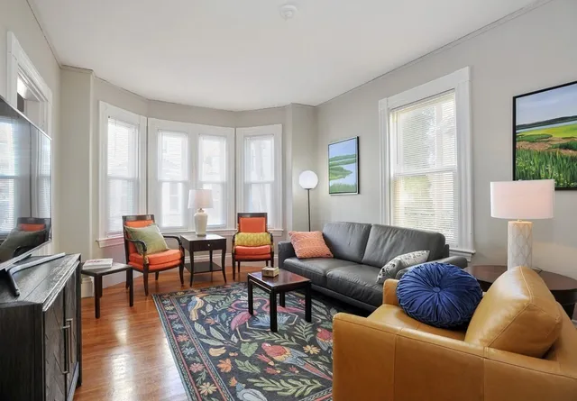 a living room with furniture wooden floor and a large window