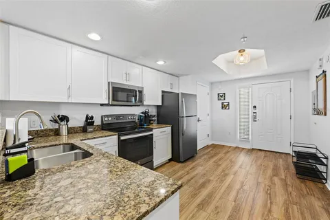 a kitchen with stainless steel appliances granite countertop white cabinets a sink and dishwasher