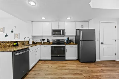 a kitchen with a refrigerator a stove top oven and white cabinets
