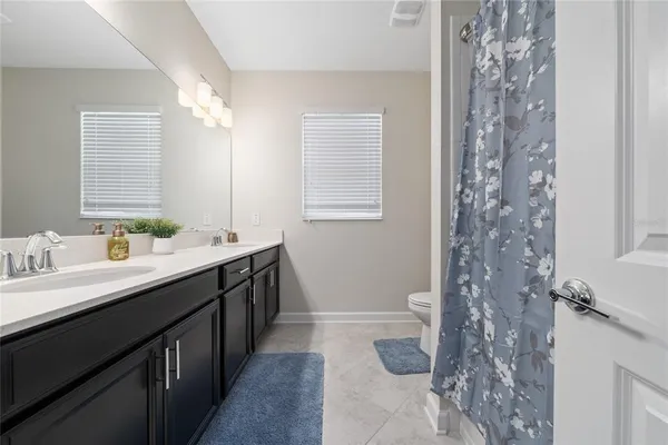 a bathroom with double vanity sinks a toilet a mirror and shower