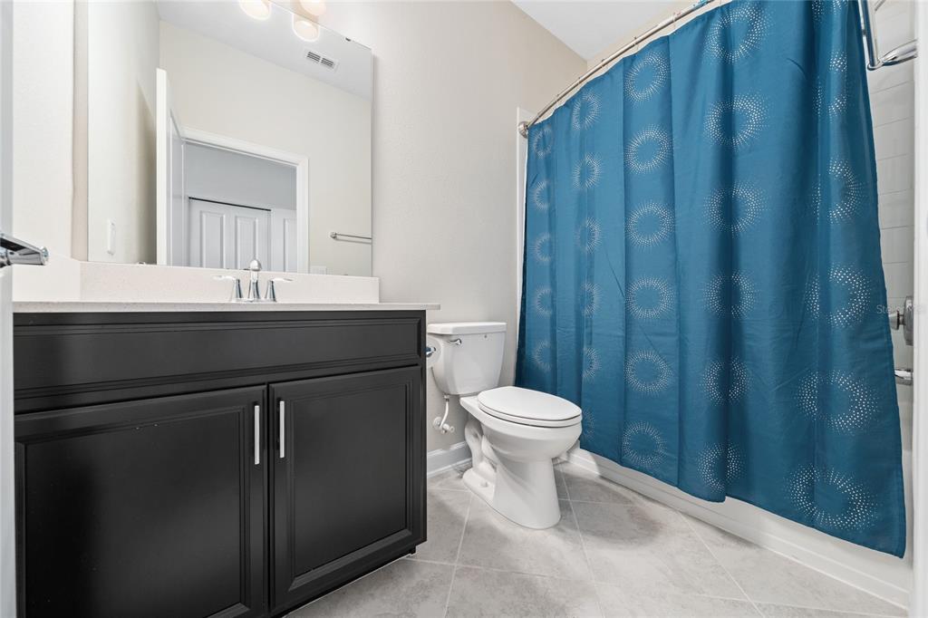 1701 Snapper Street St. Cloud, FL 34771 - Photo 4 of 29 a bathroom with a sink a toilet a mirror and shower curtain