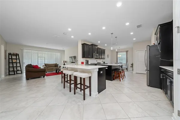 a kitchen with stainless steel appliances kitchen island granite countertop a table chairs sink and cabinets