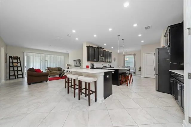 a kitchen with stainless steel appliances kitchen island granite countertop a table chairs sink and cabinets